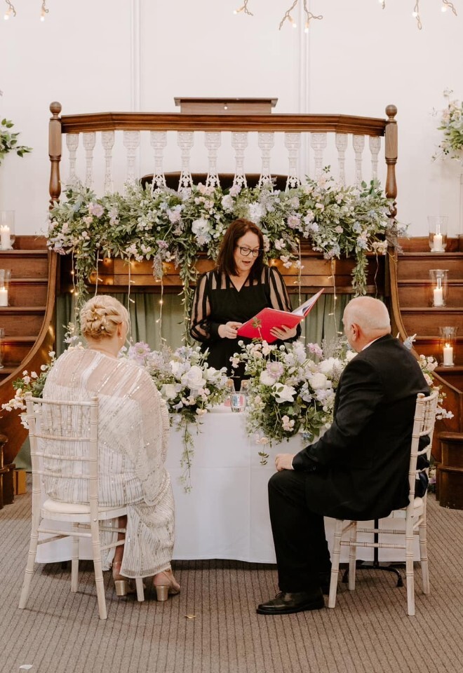 Sallieann conducting a wedding ceremony inside the Kings Chapel. The bride and groom are seated at the alter