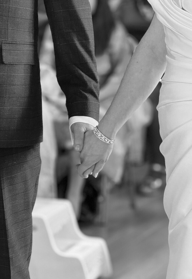 black and white image of bride and groom holding hands