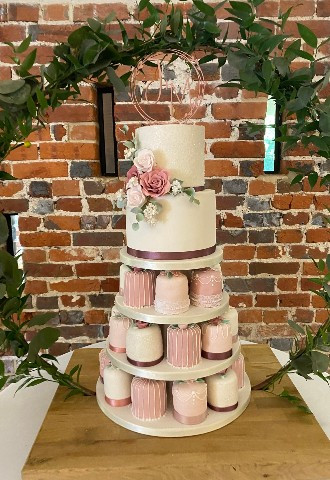 Two tier wedding cake with three tiers of min cakes in pastel pinks and white