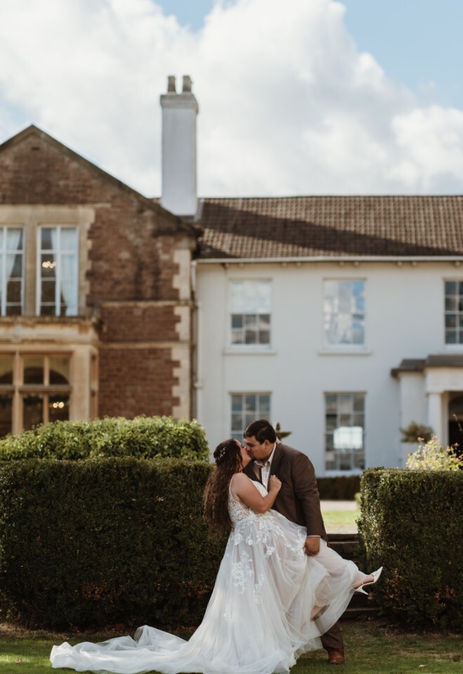 A countryside wedding venue, a happy couples in front of Glewstone Court