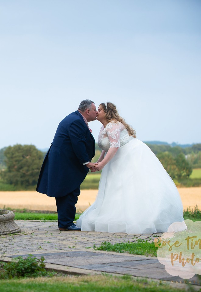 Newly married couple kiss by a fountain at the stunning Hothorpe wedding venue, Leicestershire 