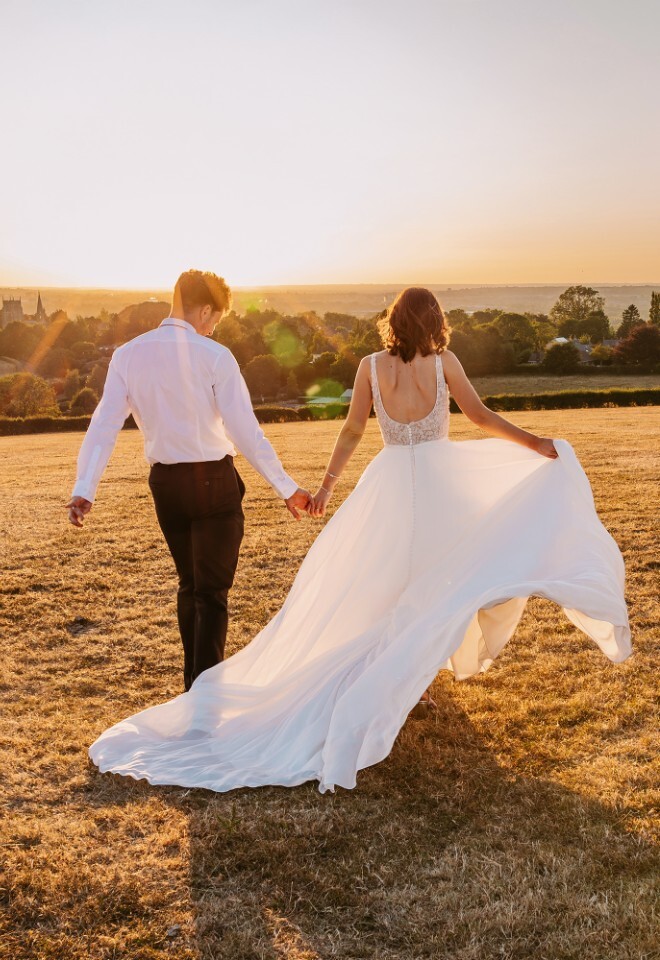 Relaxed bride and groom walking through the Cotswolds countryside, with natural golden hour wedding portraits