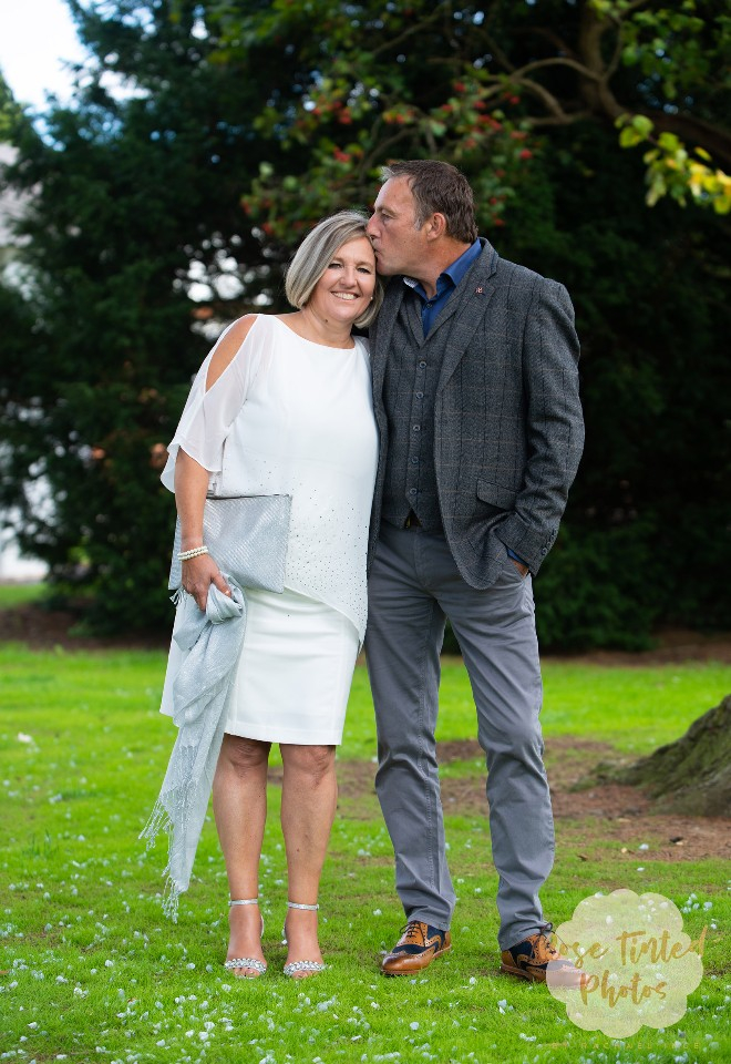 Newlywed groom kisses his brides forehead under a tree outside the Registry Office at Leicestershire County Hall