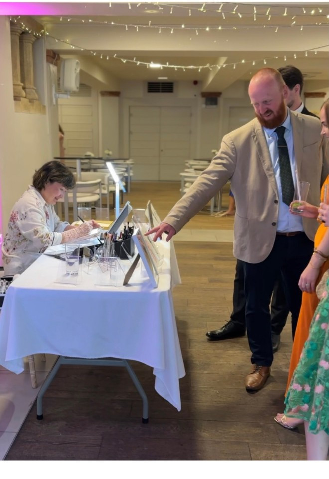 GUESTS ENJOYING THE ILLUSTRATION DISPLAY ON THE WEDDING DAY