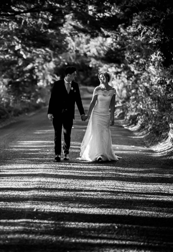 Black and White of bride and groom walking down a lane