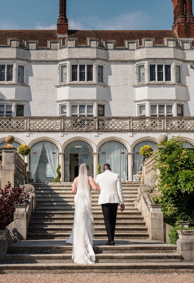 Bride and groom walking up the steps at Danesfield House Hotel on their wedding day.
