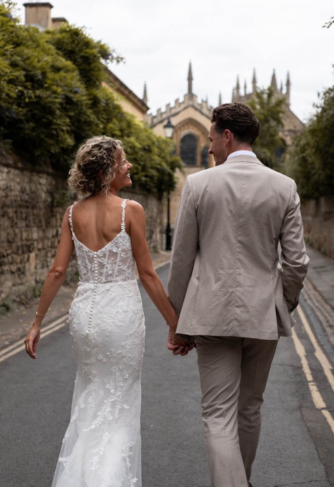 A bride and groom walk through Queens Lane in central Oxford.