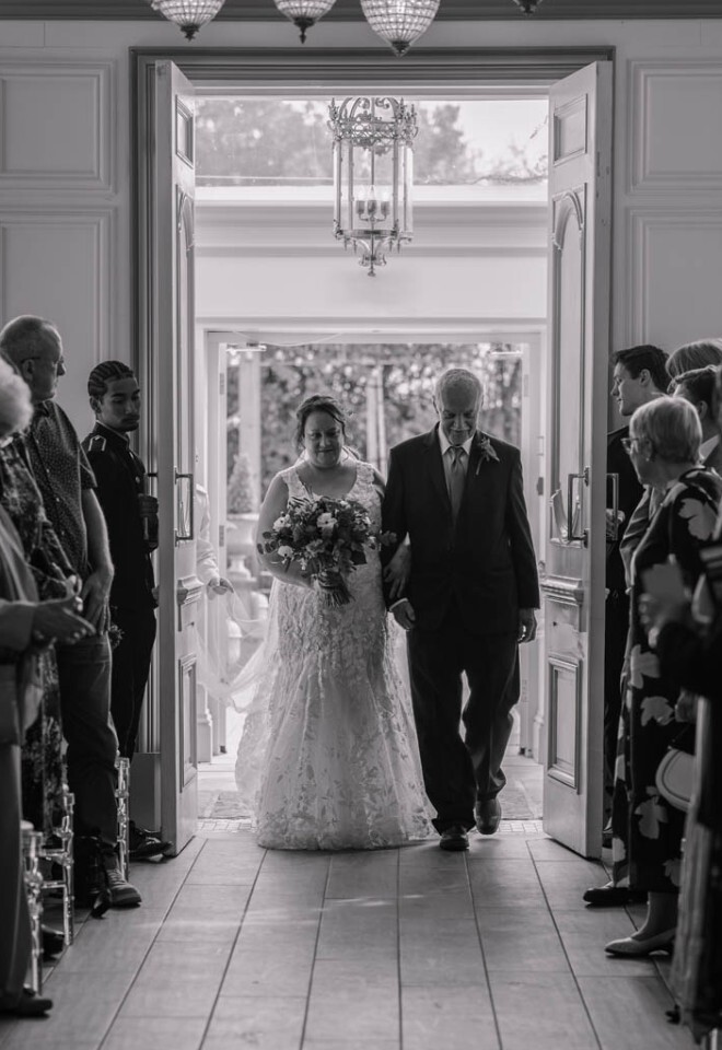 A bride walking into a ceremony at Friern Manor, Essex.