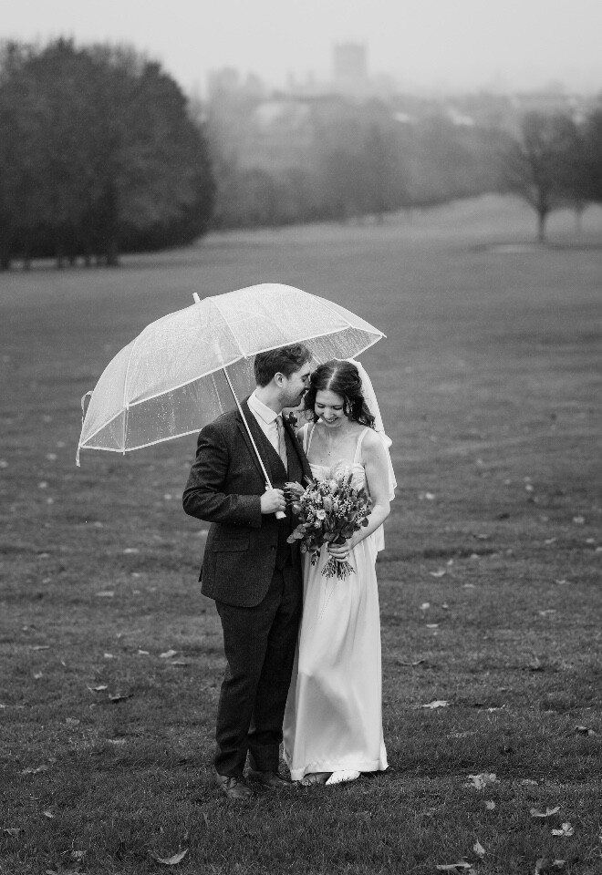 Bride and groom sharing a quiet moment under an umbrella at Tewkesbury Park wedding in Gloucestershire.