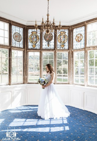 Bride stood in front of the bay windows at Bisham Abbey, Berkshire
