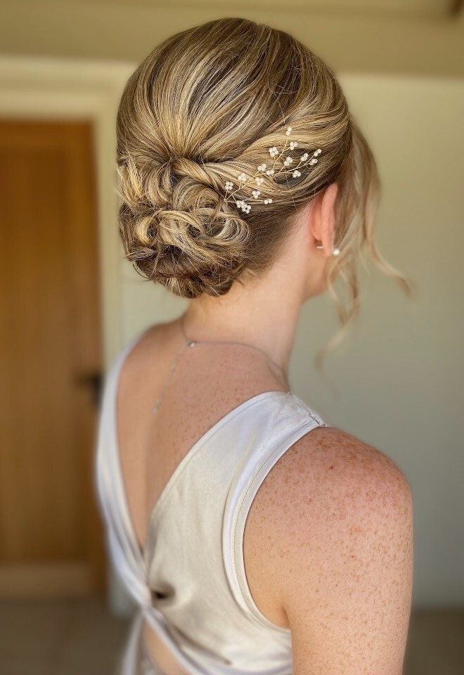 Wedding hair by Lauren Cohen Hair and Make-up Artist in Oxfordshire, featuring a low bridal bun with soft twists and delicate pearl hair pins
