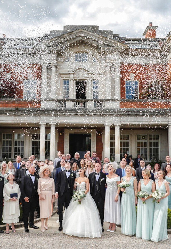 wedding group photo with confetti in the air being thrown