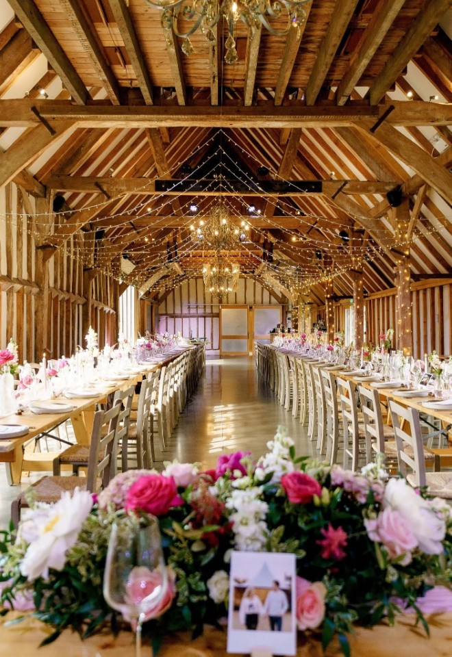 Beautifully dressed barn with pale & hot pink glowers, fairy lights in the ceiling at Southend Barns, Chichester, Sussex