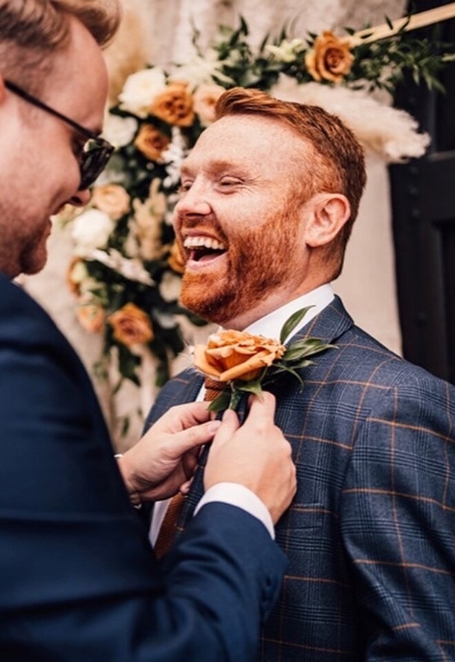 Groom buttonhole and floral arch in the back.