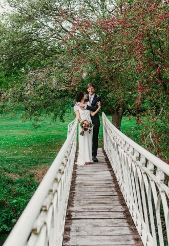 Bride and groom pose on the bridge at Nether Winchendon House, Buckinghamshire