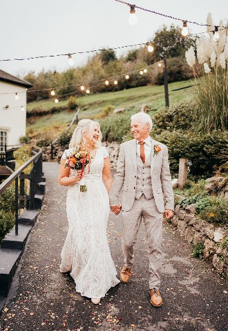 Wedding venue in Devon, bride and groom walking hand in hand at Bickley Mill Inn, Devon