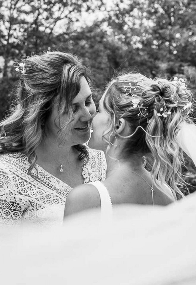 Romantic black and white photo of two brides about to kiss with veil flowing