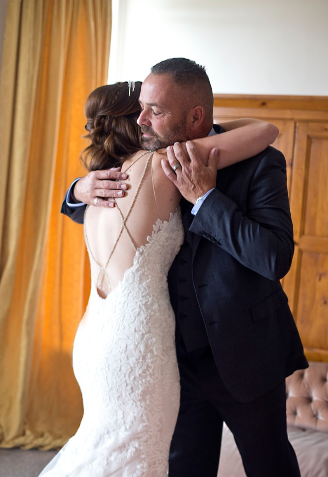 a father embraces his daughter, the bride in an intimate first look. 
