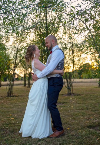 wedding couple hug each other face to face under willow cathedral in golden hour light