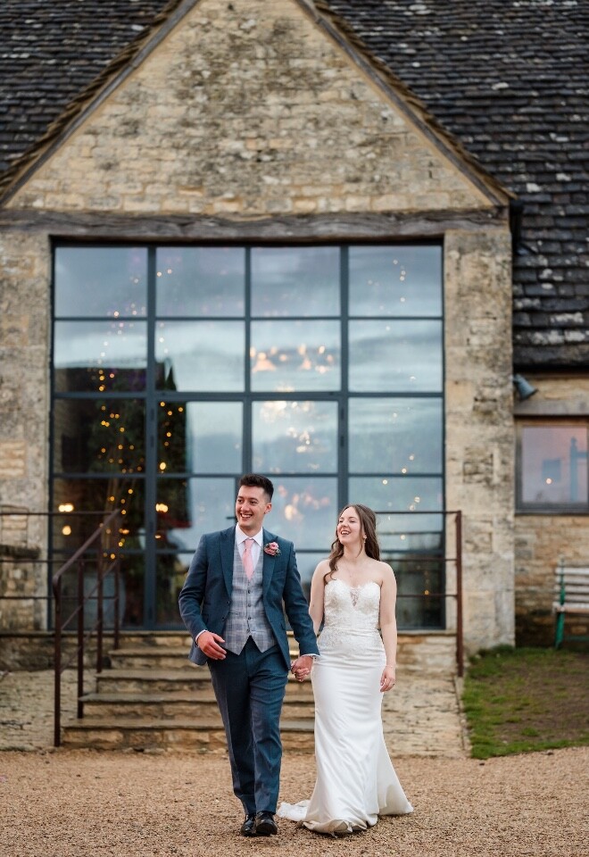 Bride and groom walking hand in hand outside The Old Gore in Cirencester on their wedding day.