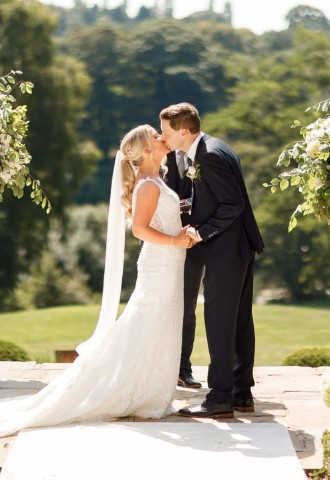 Bride and groom share their first kiss at their outdoor wedding ceremony at Delamere Manor
