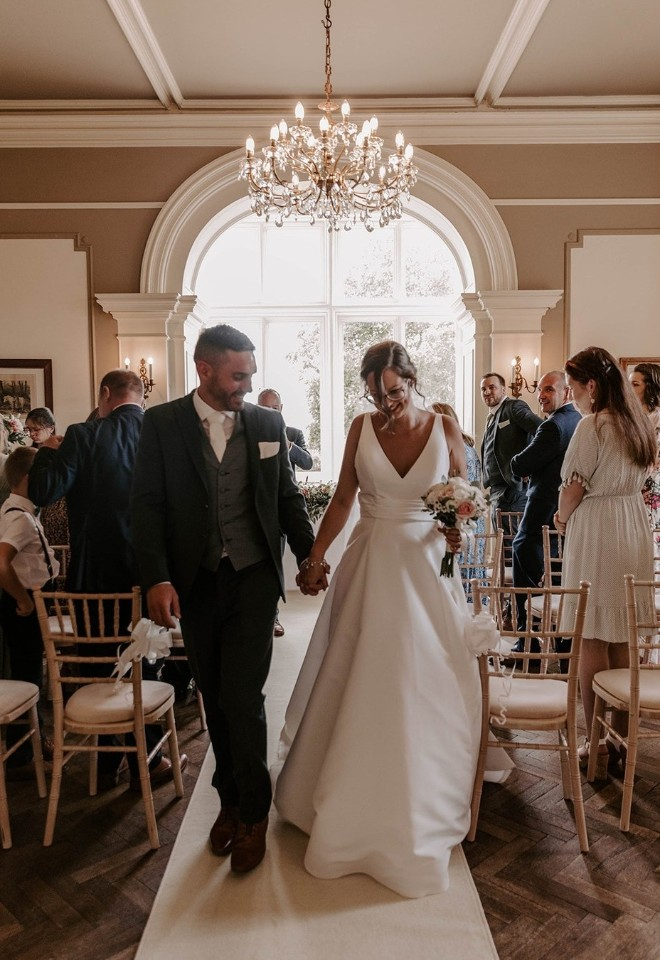 Bride and groom holding hands walking down the aisle at Glewstone Court Country House in Herefordshire