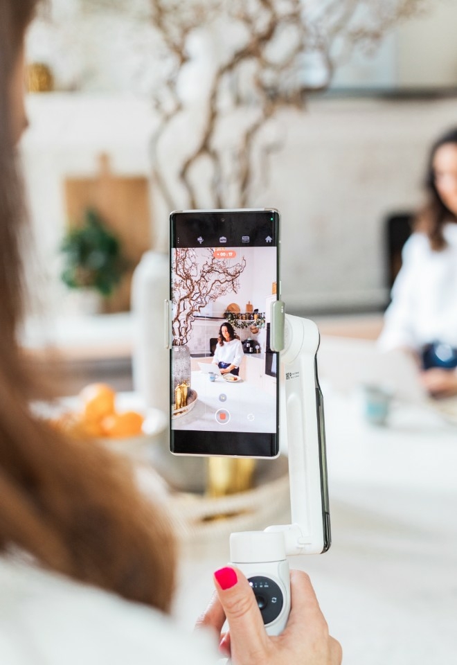 A wedding content creator based in hampshire holding a gimbal and a smartphone