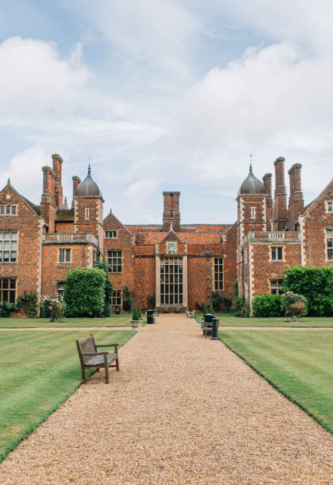 North Mymms Park wedding venue in Hertfordshire, featuring a historic Elizabethan-style mansion, manicured gardens and a gravel pathway leading to the entrance.
