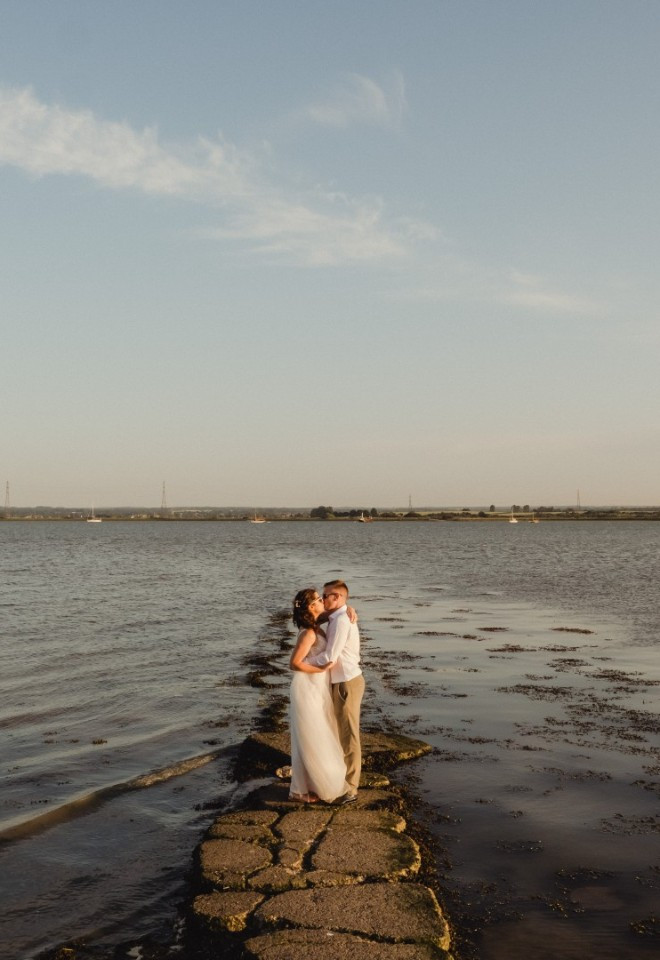 Bride and groom share a kiss by the Kent estuary at Harty