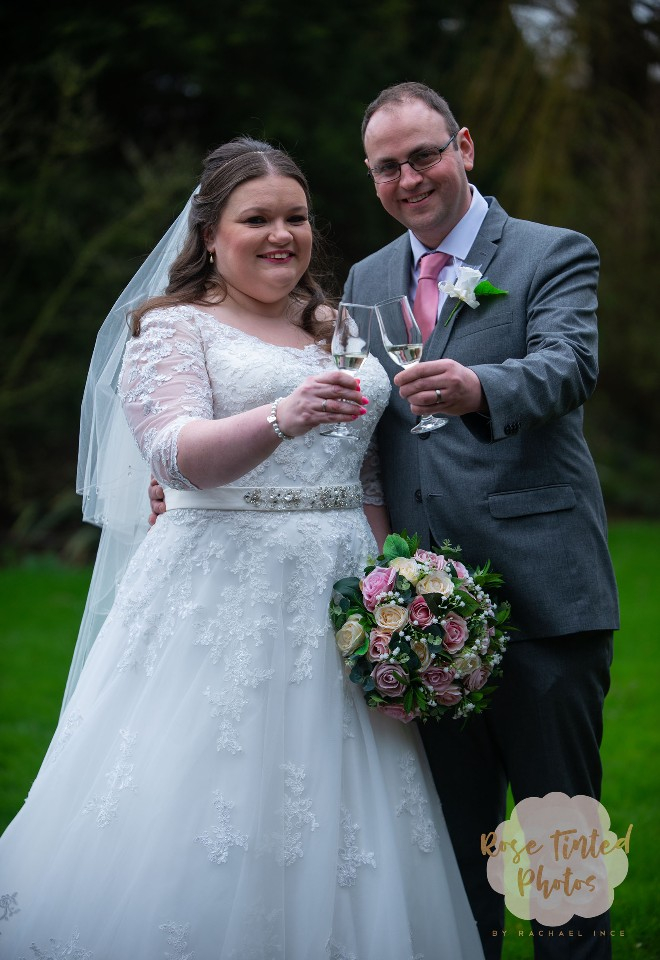 Newly married bride and groom chink champagne glasses to celebrate their wedding day
