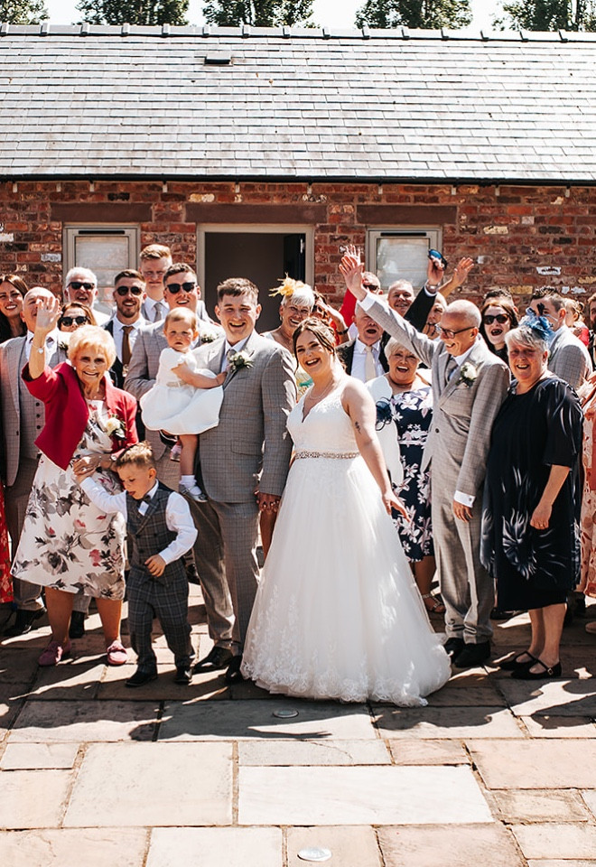  Bride, groom and their wedding guests gathered for a group photograph in the courtyard at The Cock O’Barton.