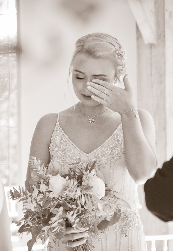 Bridesmaid wipes the tears from her eyes after watching her mother walk down the aisle 