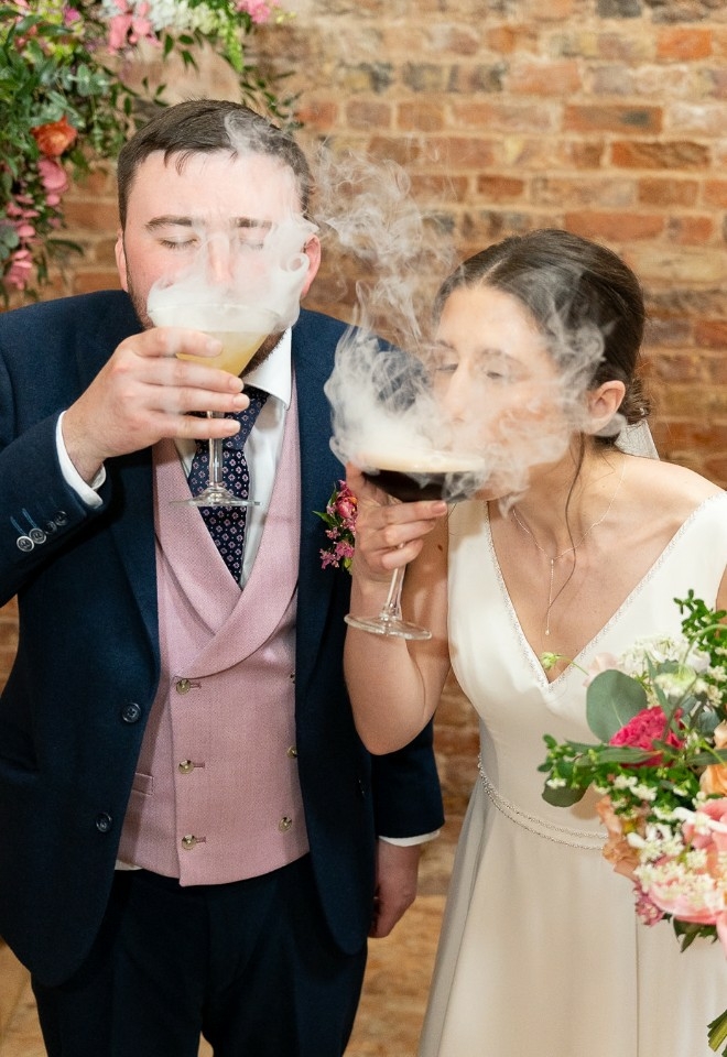 Groom & Bride sipping on smoky cocktails, the smoke enveloping their faces