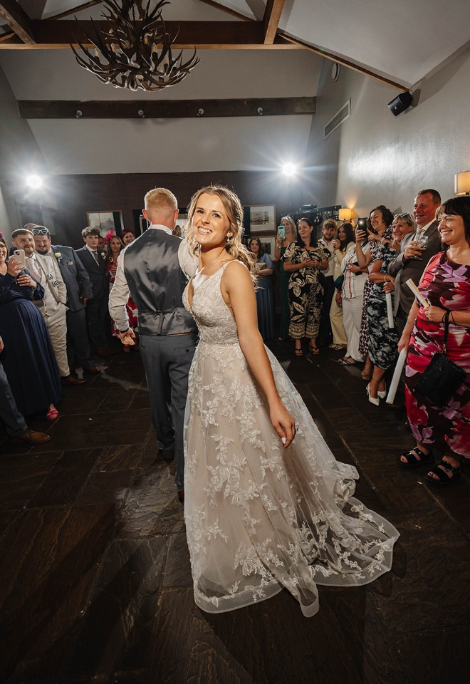 Bride and groom taking to the dance floor for their first dance, surrounded by their wedding guests at The Cock O’Barton.