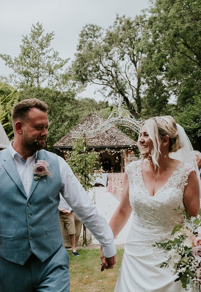 Bride and groom walking through confetti line with bridal bouquet at Somerset wedding by FLOWERS BY ANYA