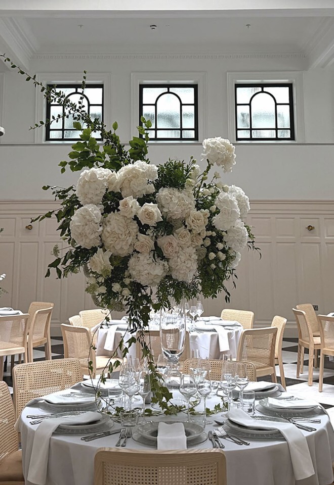Wedding breakfast tables with floral centrepieces beneath the glass-domed ceiling at The Collector’s Hall in Glasgow