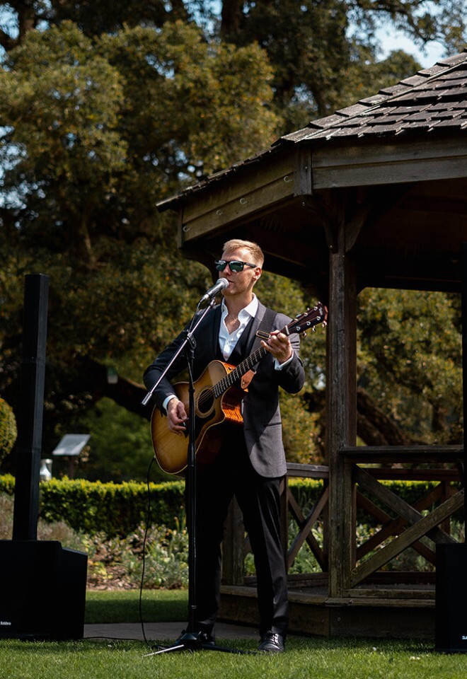 Matt Rayner, a wireless roaming musician performs at a Wedding in Essex dressed in a grey suit