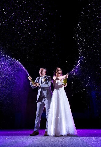 champagne spraying newlyweds celebrate their marriage at their wedding reception venue
