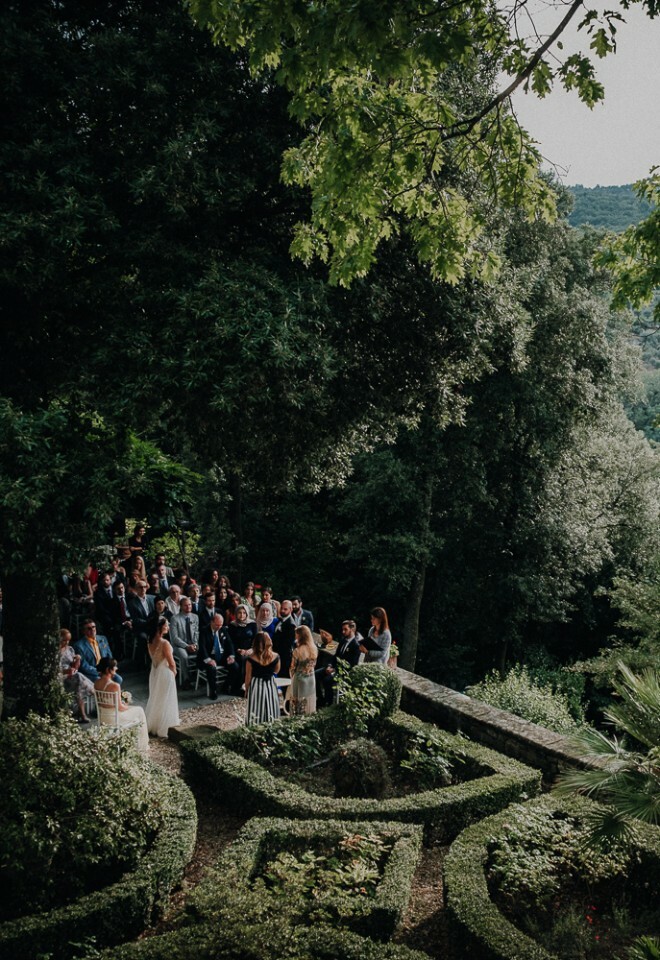 Outdoor wedding ceremony in a lush garden setting, surrounded by greenery and overlooking a scenic landscape – natural and documentary-style wedding photography