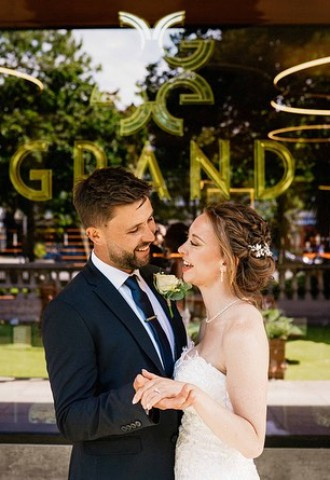 Bride and groom stand outside The Grand on their wedding day