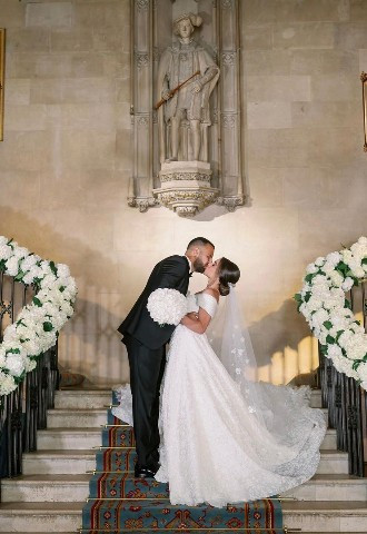 Wedding couple photo on staircase strung with flowers at Ashridge House
