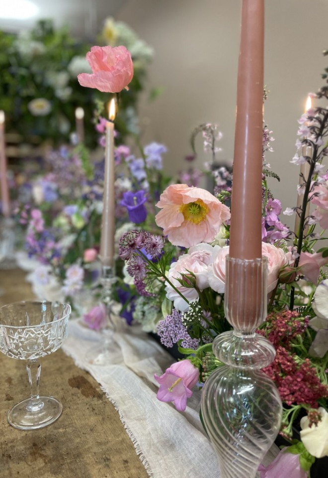 Wild Fig Flowers wedding table flowers in Oxfordshire, with natural pink, purple and white blooms, tall pink candles and elegant glassware.