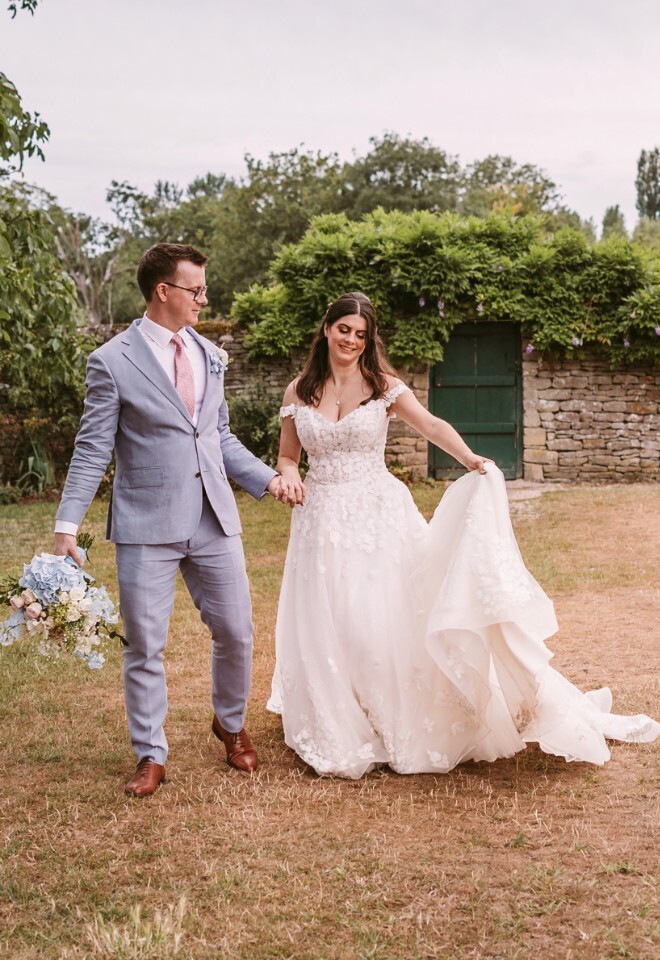 Relaxed bride and groom walking across lawn at Cogges Manor Farm 