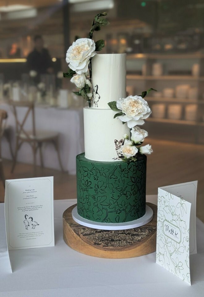 Green and white cake with custom artwork and sugar flowers