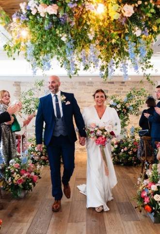 Couple walking together back down the aisle after wedding ceremony in Wild Thyme & Honey Suite