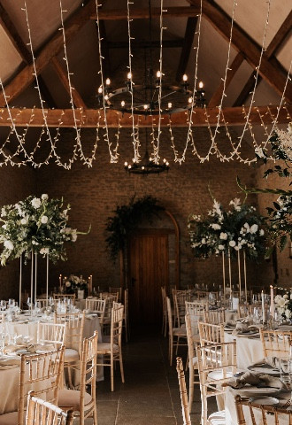 wedding barn with fairy lights and large flower arrangements in Oxfordshire
