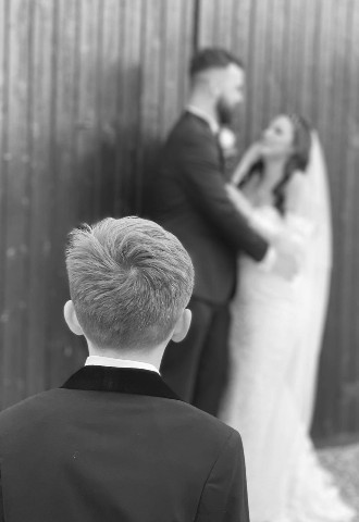 Bride and groom pose for their wedding photography whilst their son looks on, MB Events