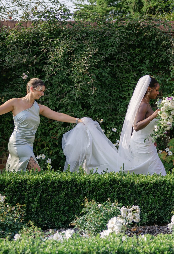 Bridesmaid holding brides trail