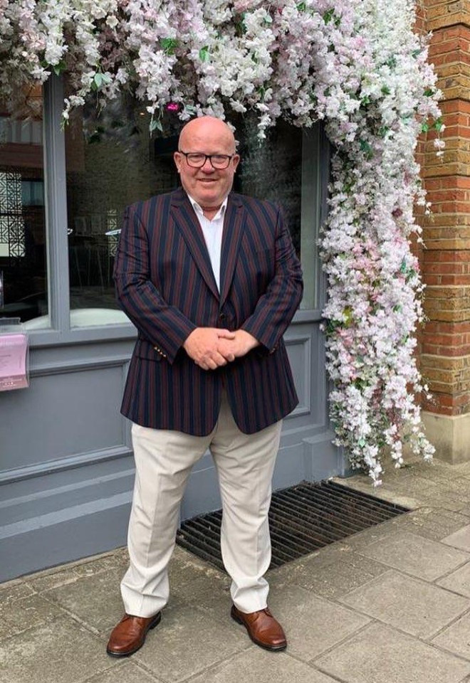 Surrey wedding toastmaster and celebrant Toastmaster John standing beneath an impressive floral display, offering a friendly and professional presence for weddings and special occasions.