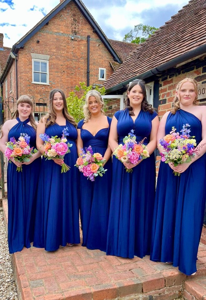 Sunning bright summer flower against royal blue dresses. Bridesmaids bouquets. 